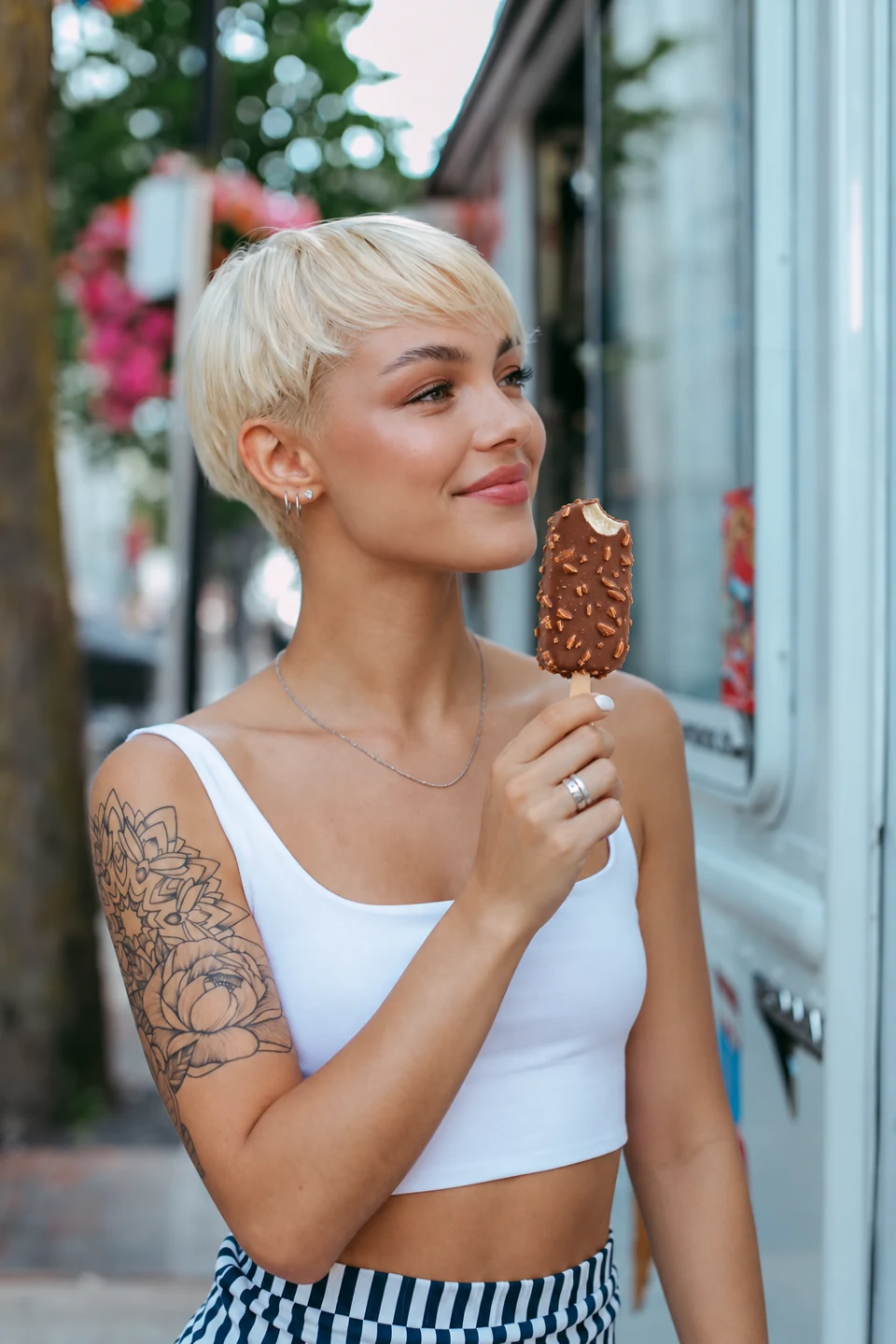 A blonde woman enjoying a chocolate almond ice cream outside a shop
